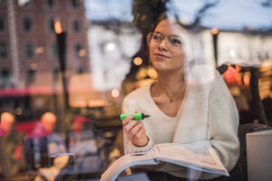 Woman staring out with a book and highlighter in hand